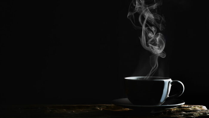 hot coffee, tea or chocolate in black cup on wooden plank